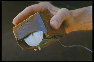Inventor Douglas Engelbart holding the first computer mouse, showing the wheels that make contact with the working surface