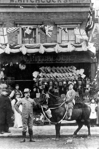 William Hitchcock, probably with his first son, William, outside the family shop in London, c. 1900; the sign above the store says "W. Hitchcock". The Hitchcocks used the pony to deliver groceries.