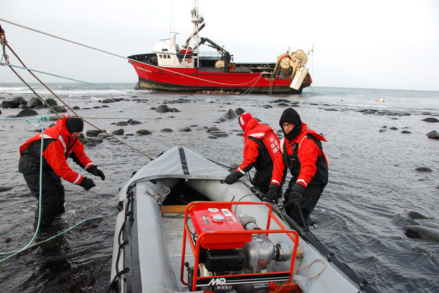 Coast Guardmen prepare to transport a portable pump to the 112-foot grounded fishing vessel Mar-Gun, March 7, 2009.