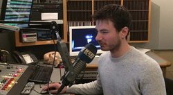 Alex Reimer while on the air speaking to a microphone.