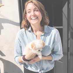 Cassandra Bodzak holding a small dog.