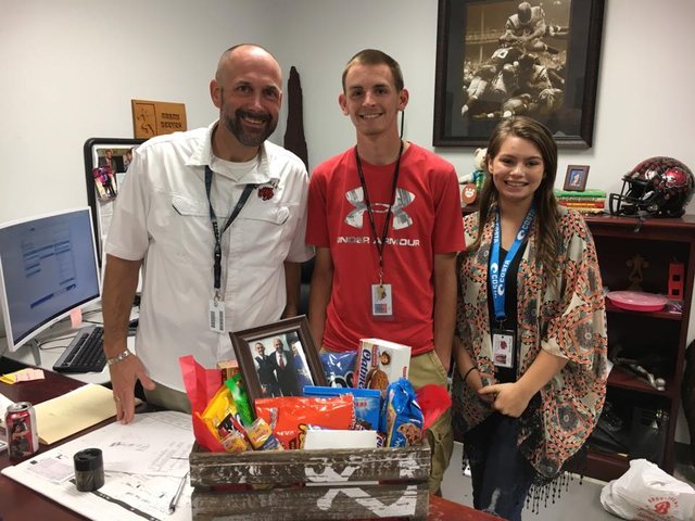 Photo of Dennis receiving a gift from a graduating students