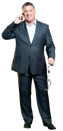 Photo of Ira Judelson holding handcuffs while talking on the phone.
