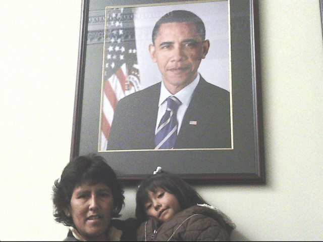 Photo of Jeanette holding one of her children with a photo of Obama above their heads.