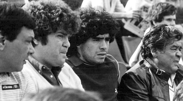 Jorge Y Diego Maradona ambos se sientan en las gradas a analizar una partida de Fútbol.