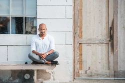 Light Watkins meditating out on the porch of a house.