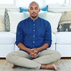 Light Watkins meditating on the floor of an apartment.