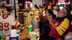 Photo of Fans celebrating an NFL game while inside of a restaurant and bar.