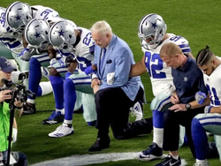 Photo of the Dallas Cowboys taking a knee with their owner.