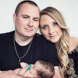 Photograph of Michael Diebold and his wife with their baby.