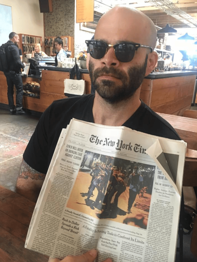 Photo of Mike inside of a restaurant with a newspaper.