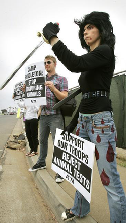 Aghdam (with a plastic sword) representing the People for the Ethical Treatment of Animals and protesting at the main gate of Camp Pendleton (photo taken on August 12, 2009; credit: Charlie Neuman/ San Diego Union Tribune )