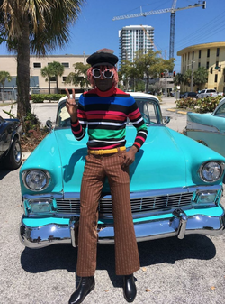 Photo of NewAge Jerkboy where he stands with a classic car from the 1960s era.