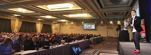 Kusmich speaking in front of hundreds of people