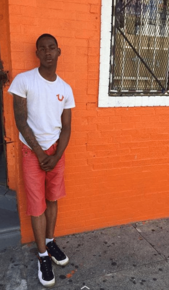 Photo of SP standing near an orange wall where it matches his shorts.