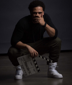 Photo of Steven Caple Jr. holding a slate in the dark.
