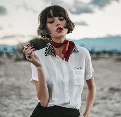 Taylor Lashae smokes a cigarette near the desert.